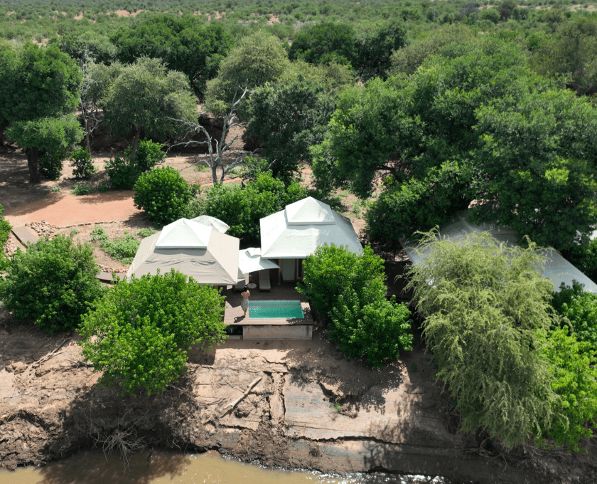 Aerial view of a house surrounded by trees and water